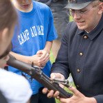A Fort Mackinac soldier showing an authentic rifle to guests.