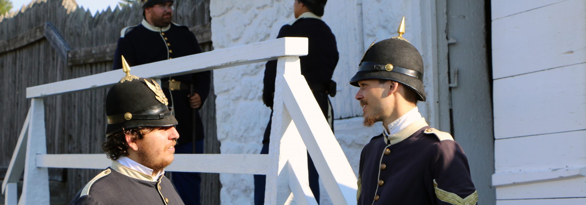 Costumed interpreters dressed as U.S. soldiers from the 1880s in front of the East Blockhouse at Fort Mackinac.