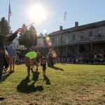 A Fort Mackinac soldier playing graces with a young guest.