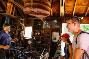 A costumed interpreter working as a blacksmith talks with guests at the Benjamin Blacksmith Shop. 