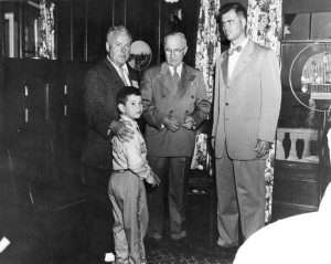 A photo of Brian and James Dunnigan standing next to President Harry Truman and Michigan Governor G. Mennen Williams in 1955. 