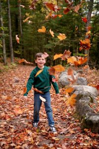 A child throwing leaves in the air in fall at Historic Mill Creek. 