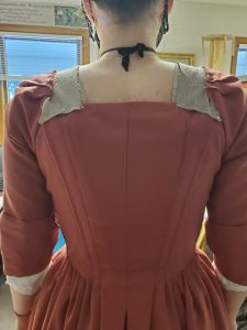 A reddish-orange dress being fitted on a staff member for Mackinac State Historic Parks. 