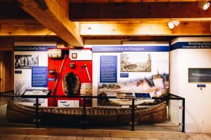 Inside an exhibit at Colonial Michilimackinac showing a canoe and exhibit panels talking about the French presence at the site. 