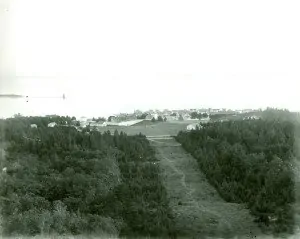 View of Fort Mackinac from Fort Holmes, ca. 1900. A portion of the grandstand is visible at the far left of the parade ground. Sergeants’ Quarters and the roof of Mon-commissioned Officers’ Quarters are visible at the bottom right of the parade ground.