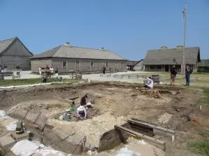 The archaeology dig site at Colonial Michilimackinac, with people in white shirts in the dig site.
