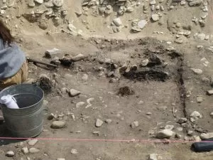 The archaeological dig at Colonial Michilimackinac with dirt, rocks, a large hole, and ropes.